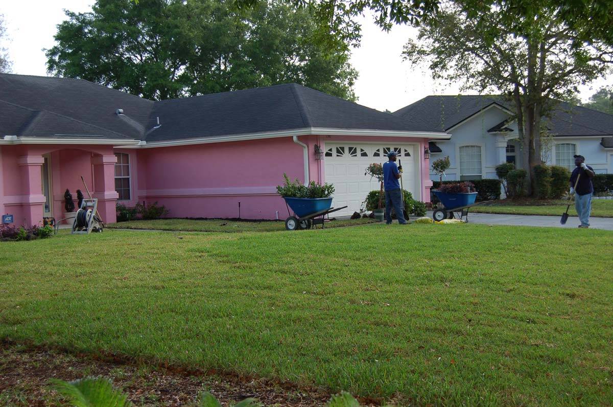 The Daniels Landscape & Irrigation LLC working on the front yard of a pink house