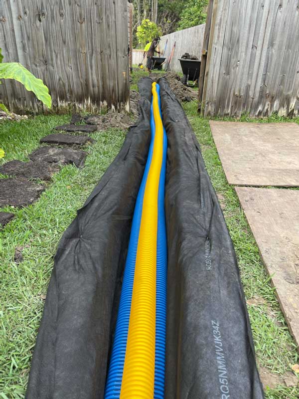 Lining a ditch with geo fabric and installing corrugated pipes
