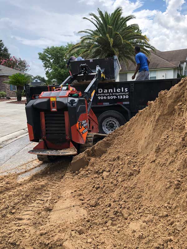 Workers from Daniels Landscaping & Irrigation LLC operating a Ditch Witch