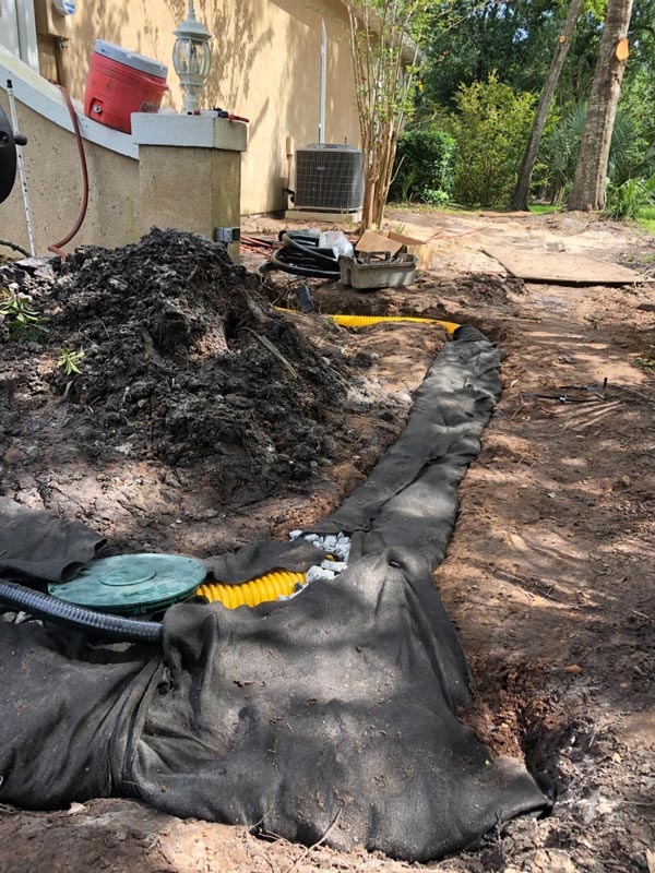 A French drain system with landscaping fabric pinned over it