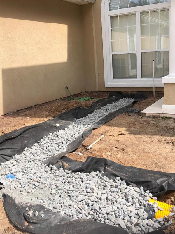 A trench with a French drain system in it, covered with rocks