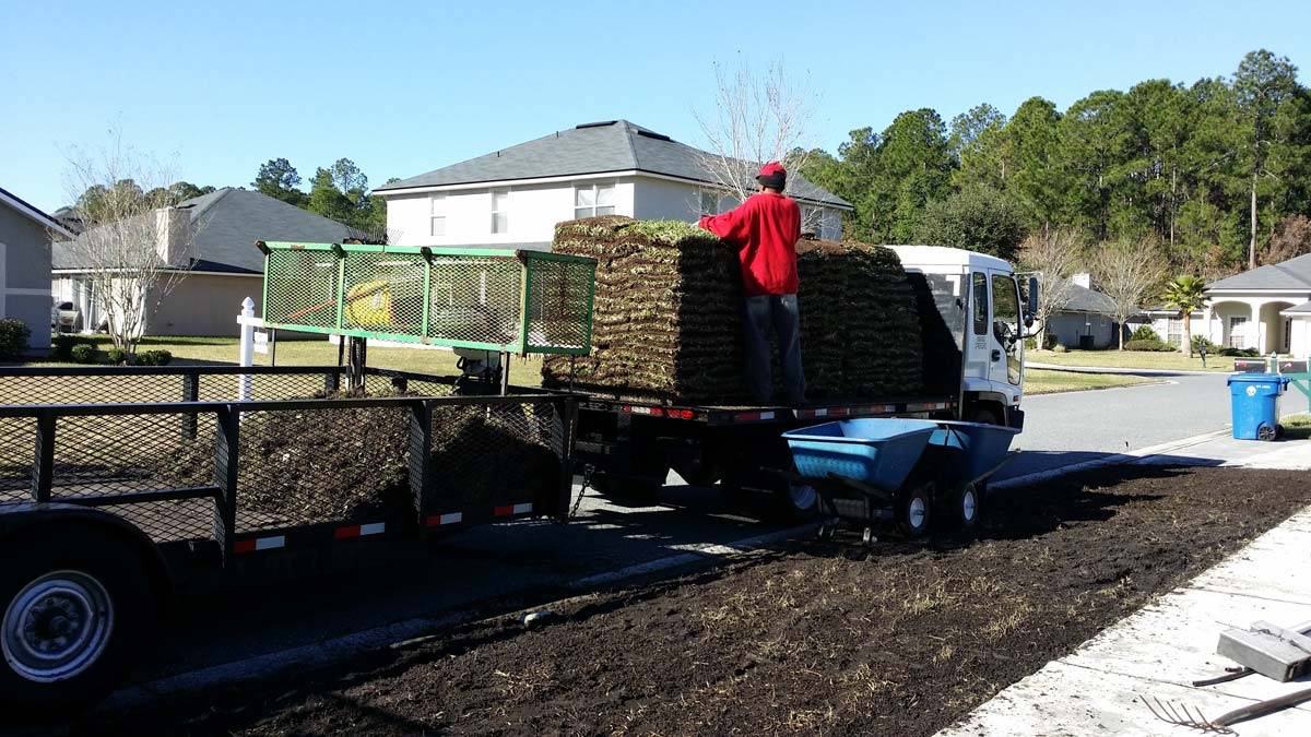 A worker on the back of the Daniels Landscape & Irrigation LLC truck, about to put down sod